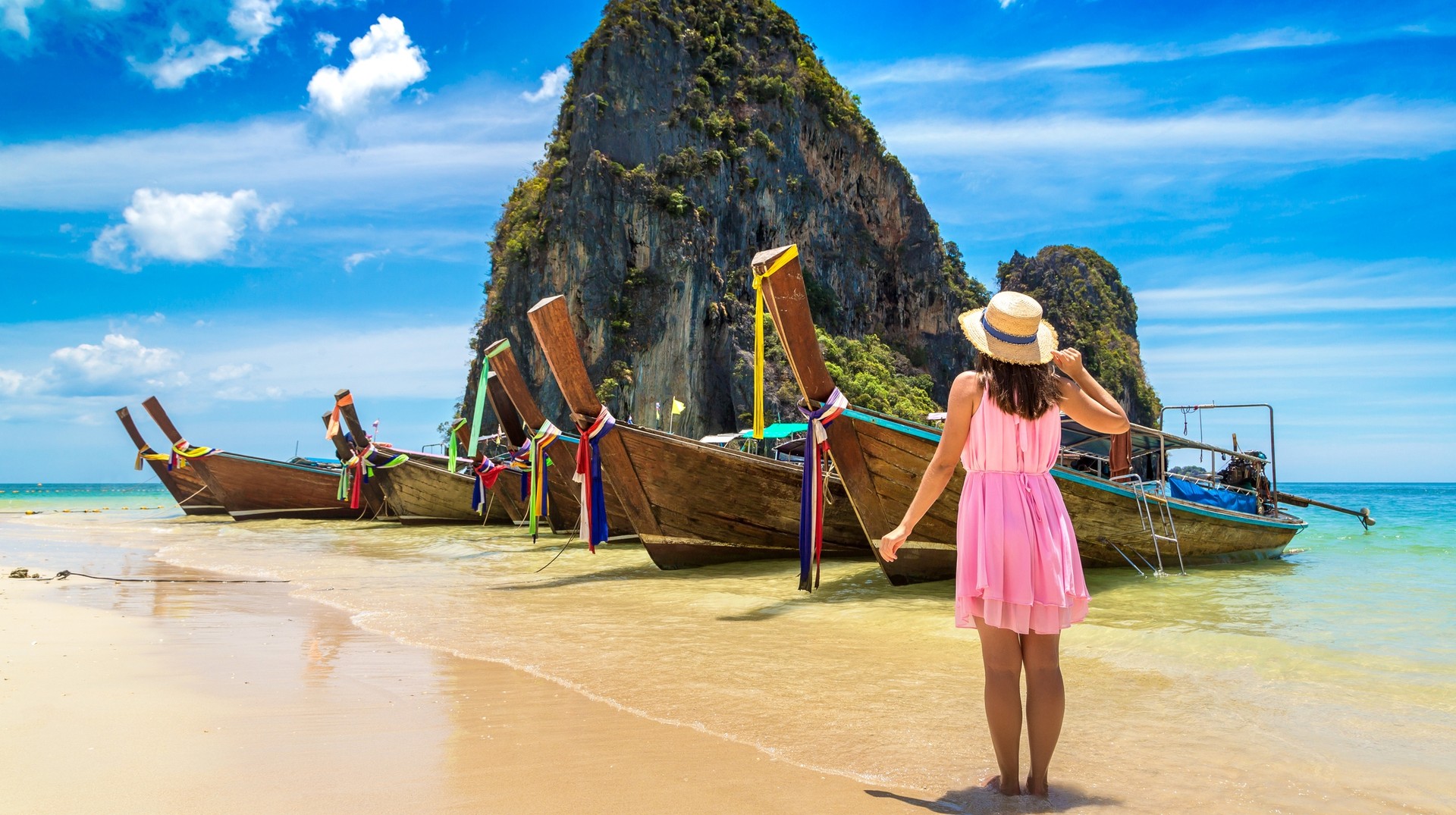 Bask in the sun-kissed beaches and relax during summer in Thailand. A tourist woman near a traditional longtail boat in Phra Nang Beach during summer in Thailand.