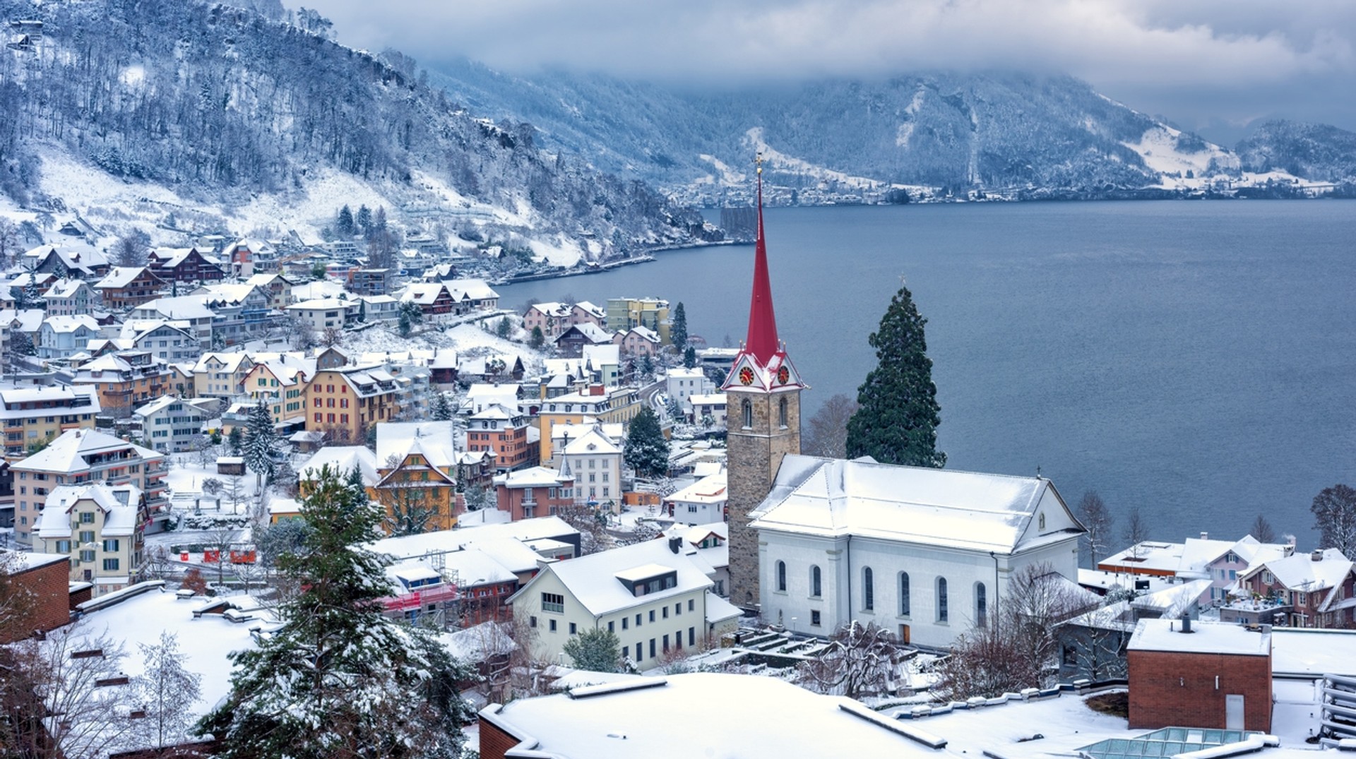 Head to Weggis village on Lake Lucerne which is covered in snow in Switzerland in February. See the roofs in Weggis village covered in snow in Switzerland in February.