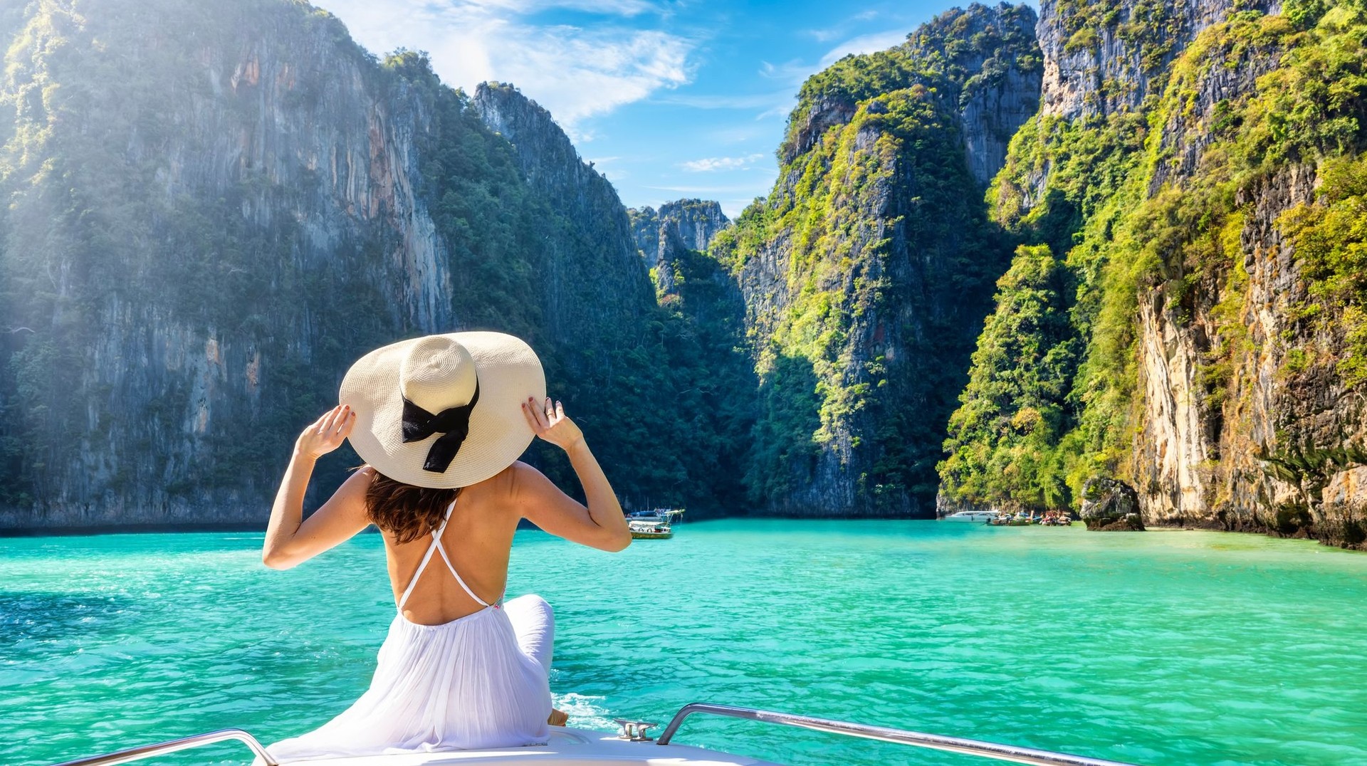 Unwind on Maya Beach in Thailand, where pristine sands and crystal-clear waters offer the ultimate slice of paradise during your 10 days in Thailland. A girl in the white dress relaxing on a boat in Maya beach during her 10 days in Thailand.