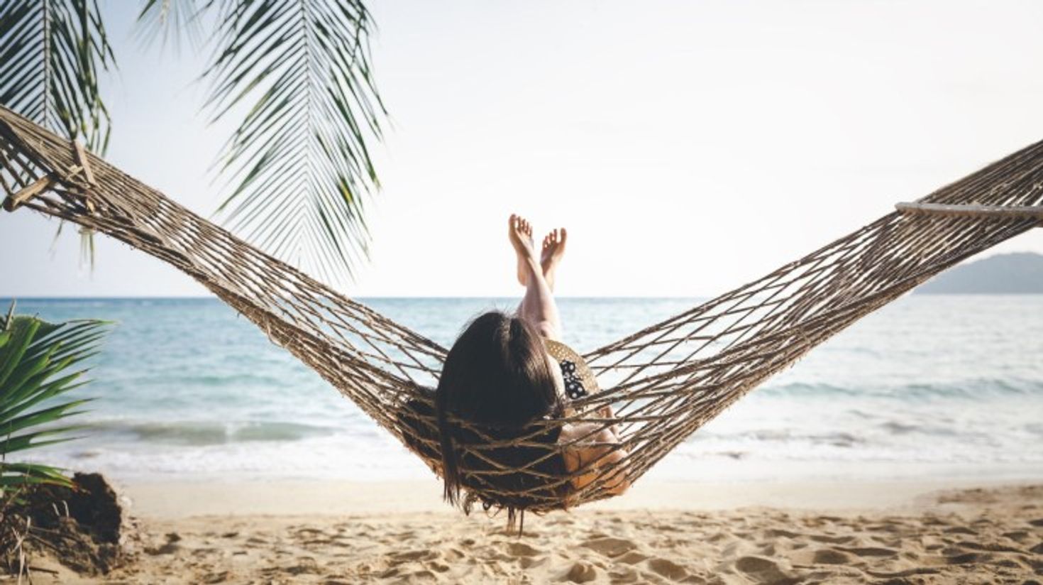 A girl relaxing in hammock on Koh Samui beach during evening in Thailand.