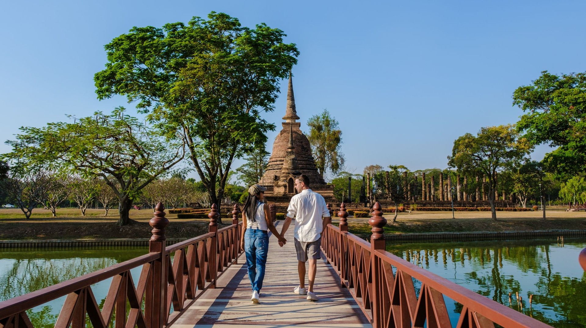 Delve into the rich heritage of Sukhothai during your 11 days in Thailand, where ancient temples and stunning ruins offer a captivating journey. A couple walking hand in hand in Sukhothai during their 11 days in Thailand.