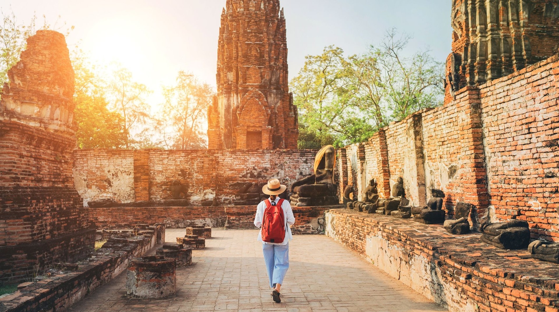 A young woman tourist walking through Ayutthaya Historical Park during dusk on her 8 days in Thailand.