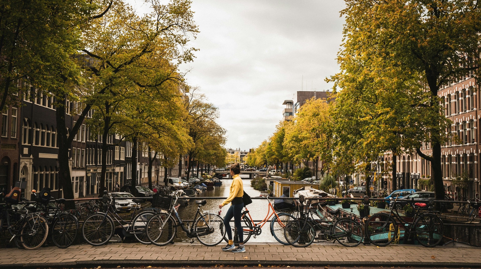 Amsterdam is known as a "Bicycle City", but it is also a great city to explore on foot. A girl walks past a bridge over a canal in Amsterdam, Netherlands