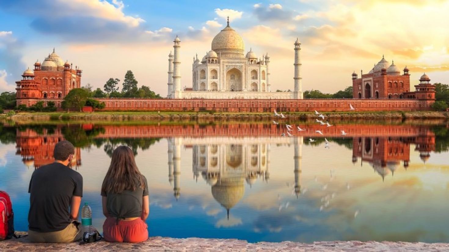 A tourist couple admiring the beauty of Taj Mahal during dusk.