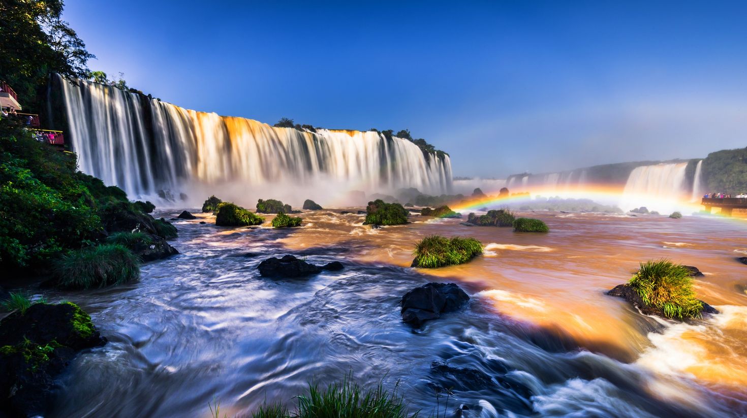 Panoramic view of Iguazu Falls with rainbow during evening.