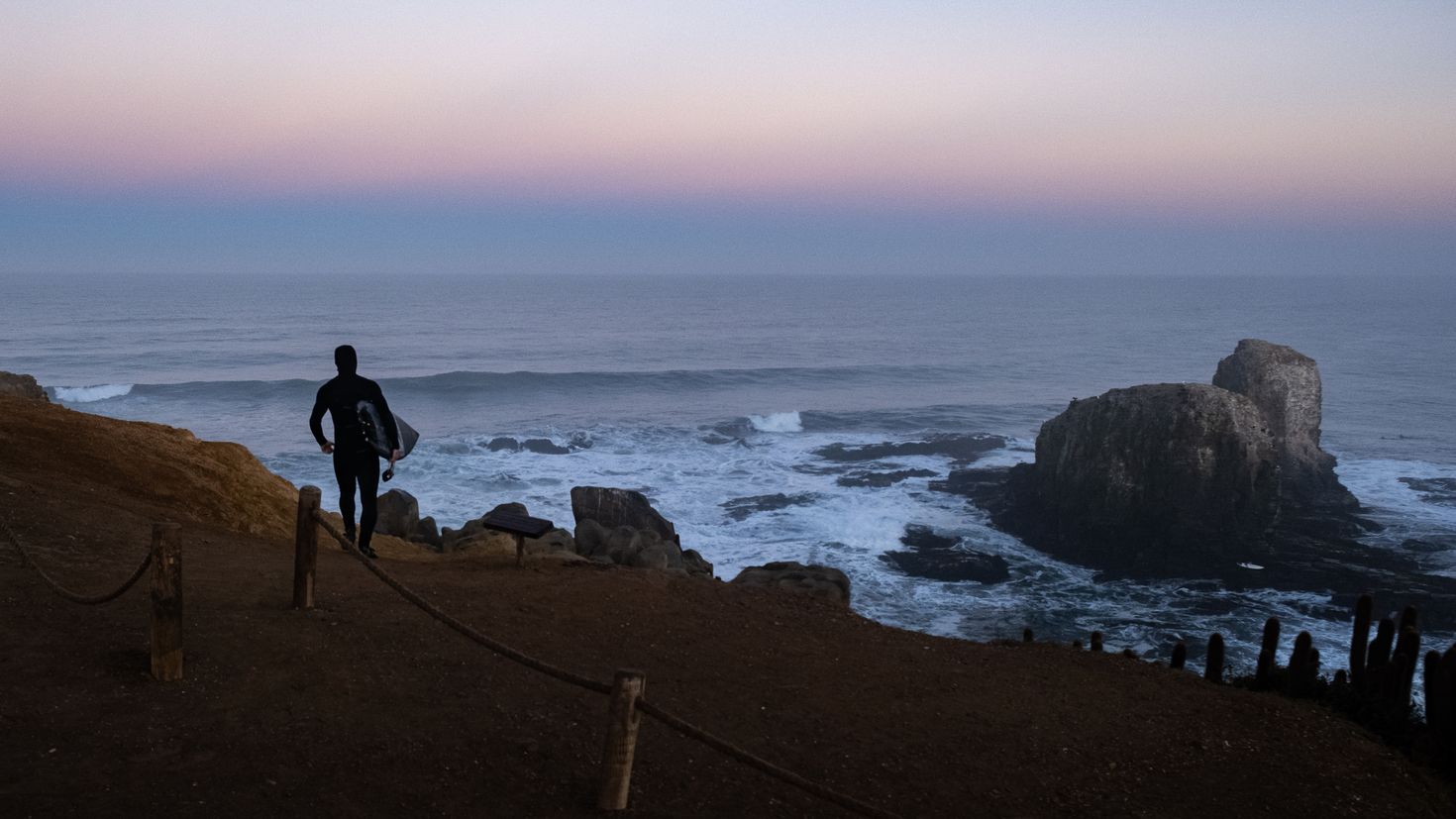 Surfer walking towards Pichilemu to surf&mdash;one of the things to do in Chile.