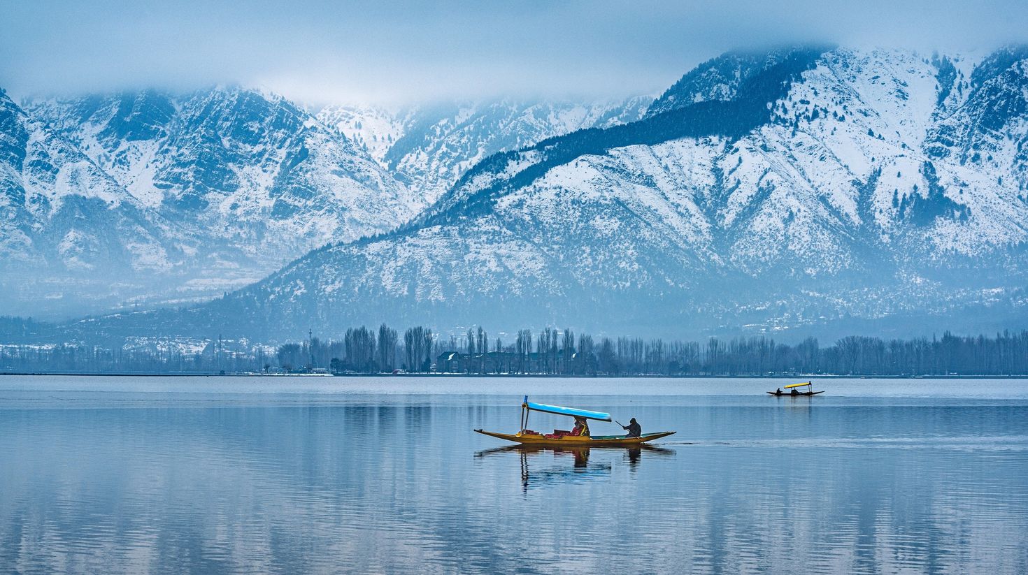 Boats on the Dal Lake with mountains in the back in Kashmir during winter