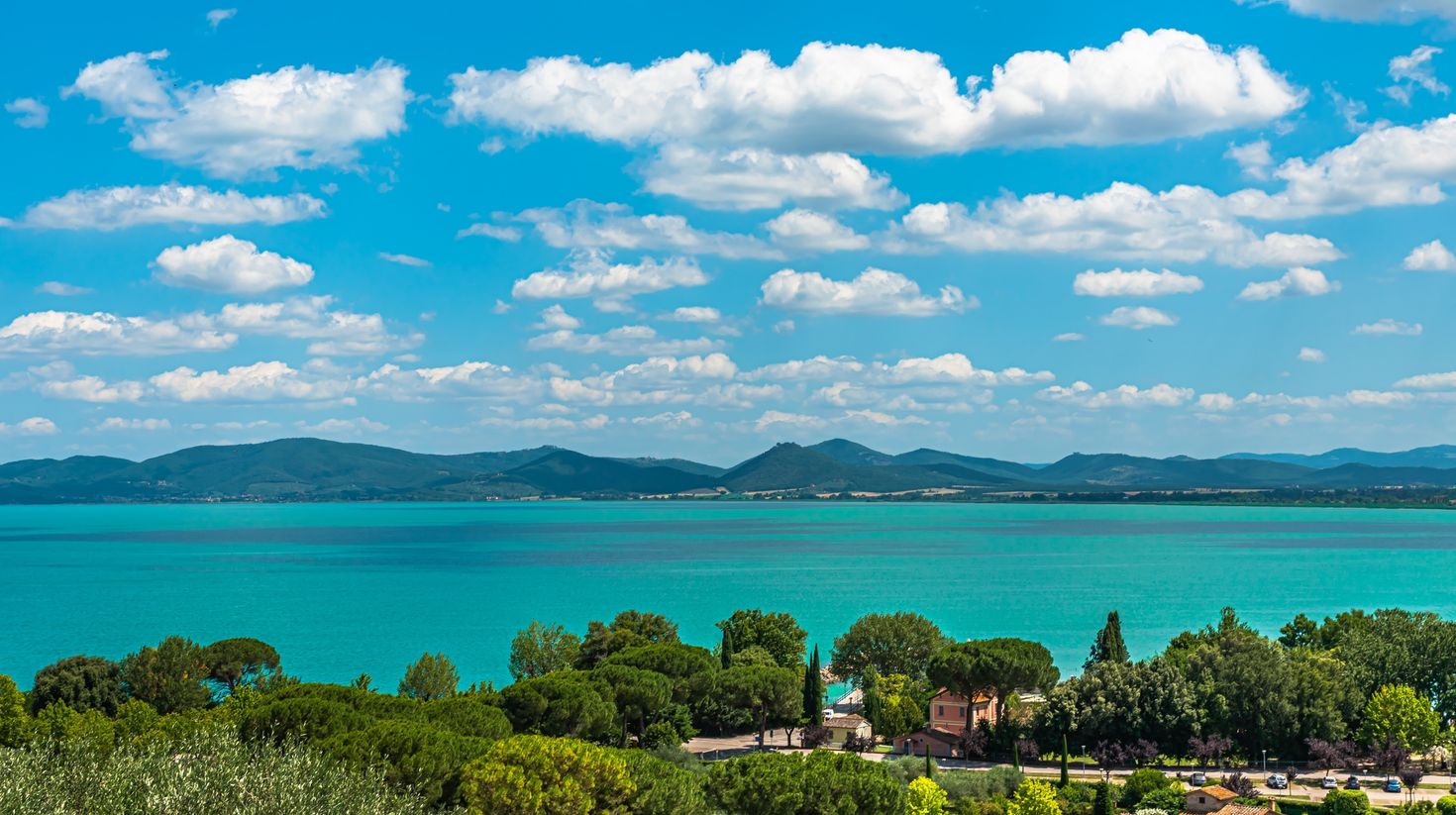 A village on the shores of Lake Trasimeno in Italy on a clear day.