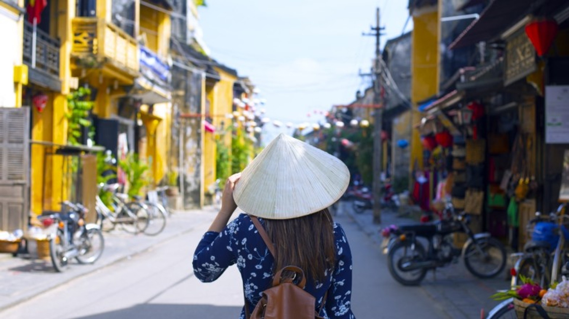 One of the best places to visit in Vietnam includes Hoi An, a well-preserved town by the river. A tourist woman exploring Hoi An, one of the best places to visit in Vietnam.