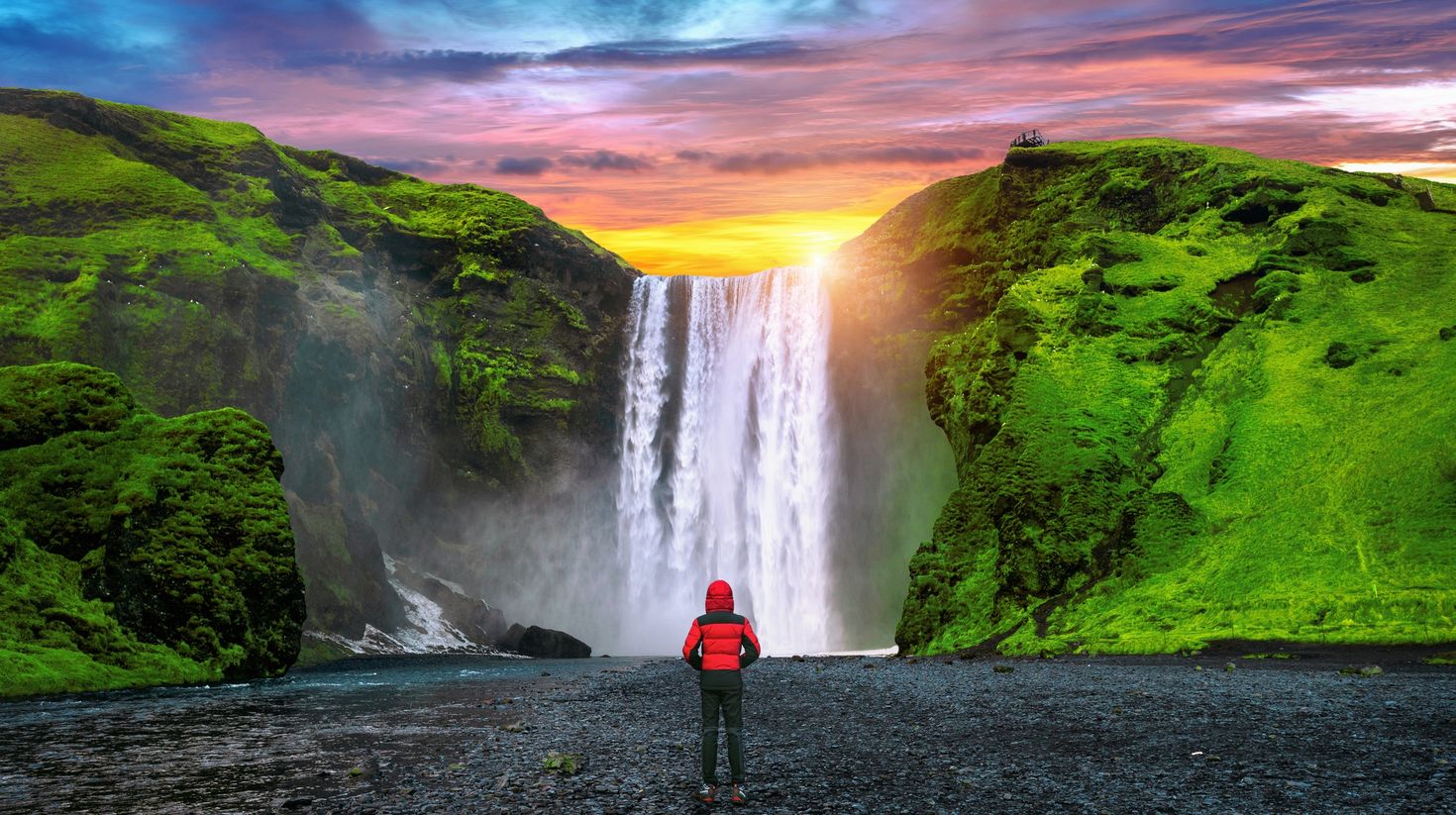 A man facing towards Sk&oacute;gafoss waterfall and admiring it.