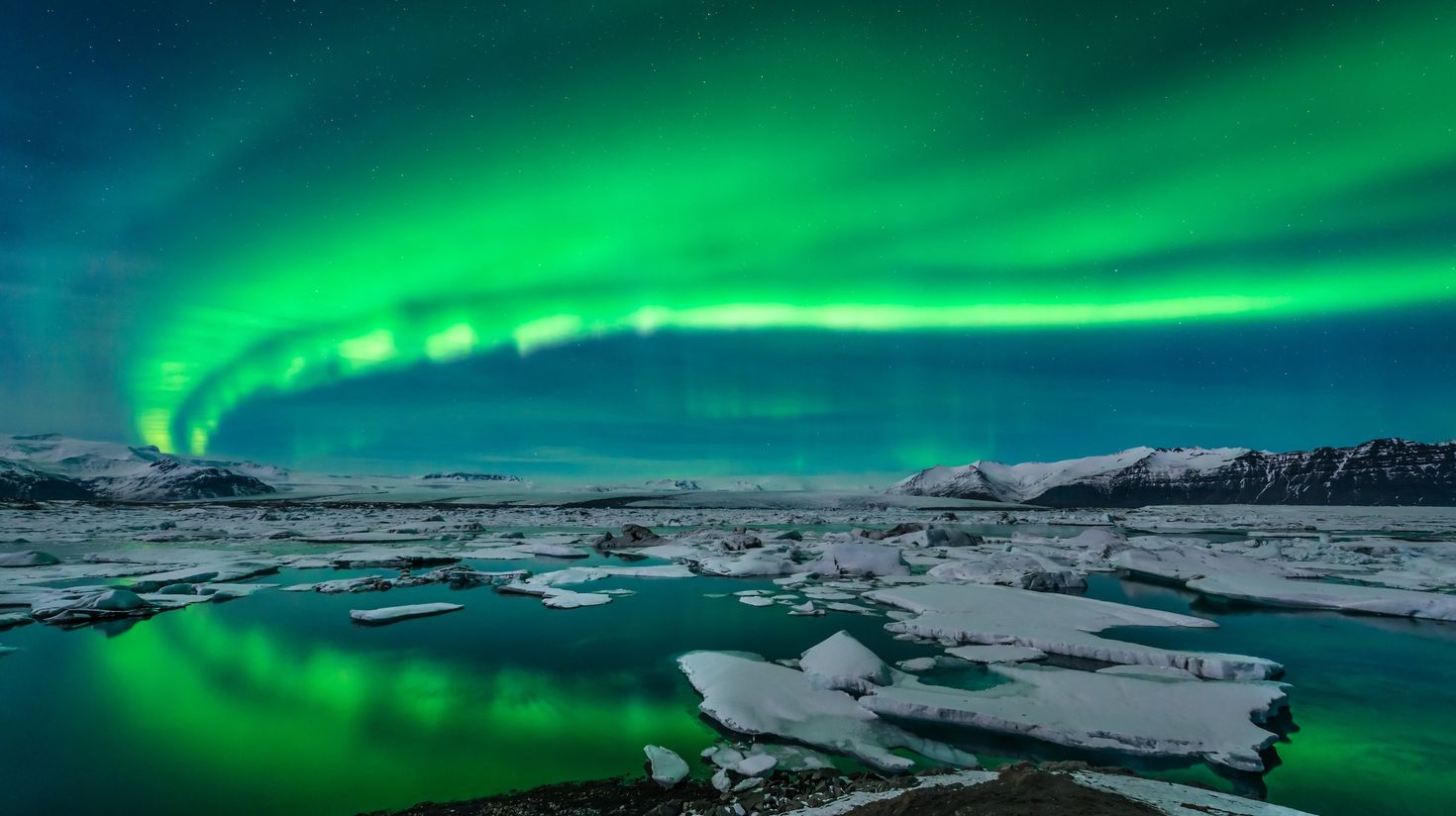 Green streaks of Northern Lights visible above Jokulsarlon Glacier.