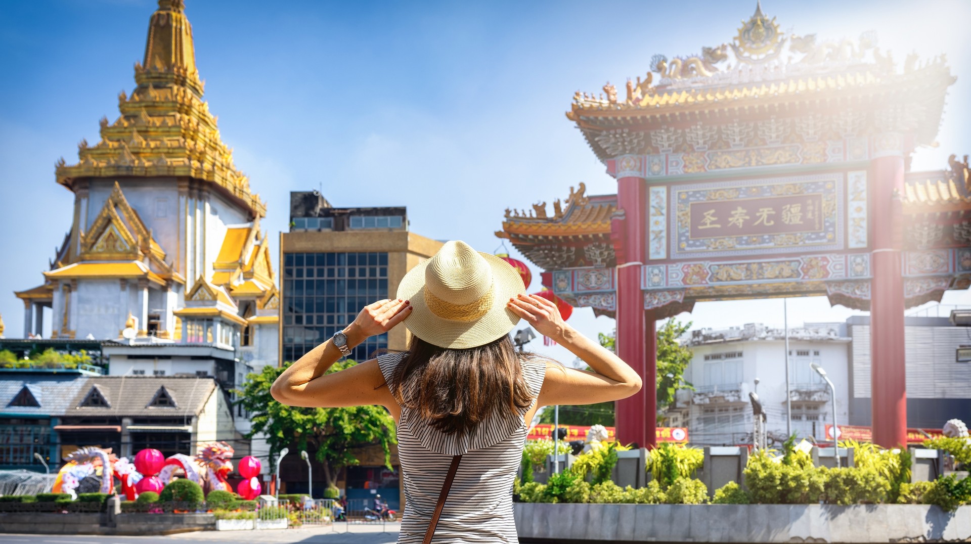 A travel influencer in Asia stands in front of Chinatown Gate in Bangkok.