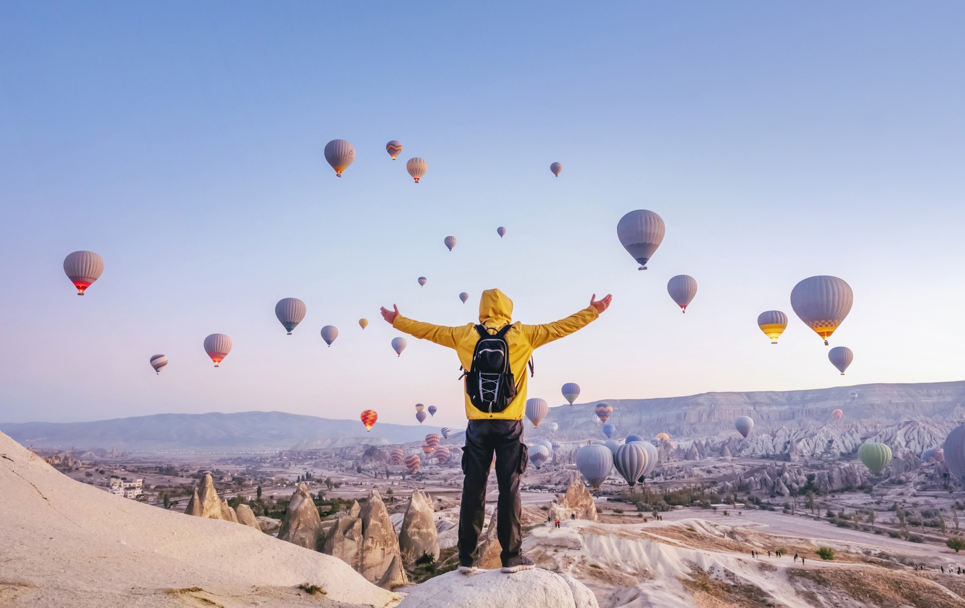 A man with open arms in Cappadocia looking at hot-air balloons while spending 10 days in Turkey.