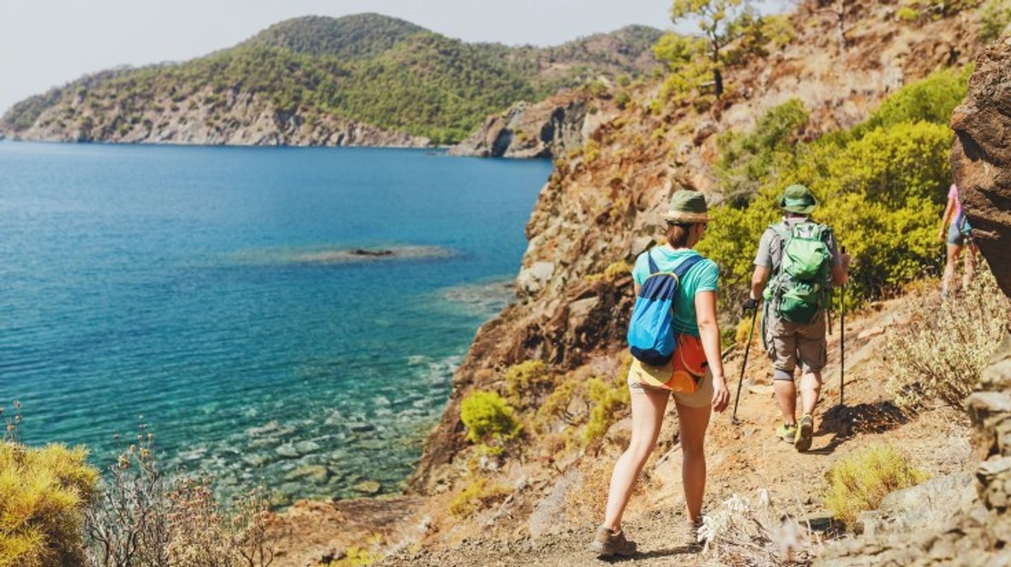 Tourists following a hiking trail on the Lycian Coast with the sea beside them.