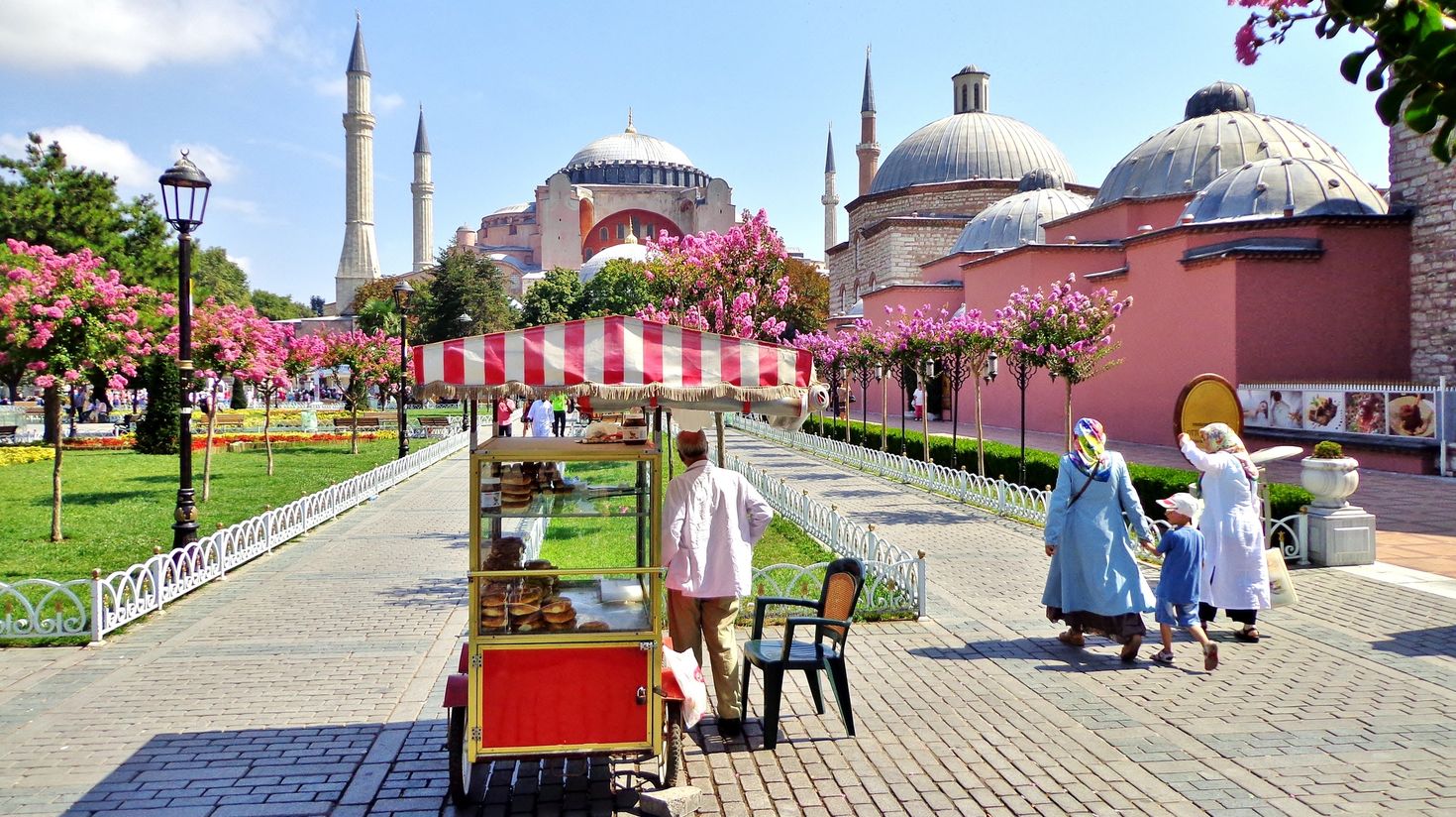 A family walking by Simit salesman on a sunny day in Istanbul.