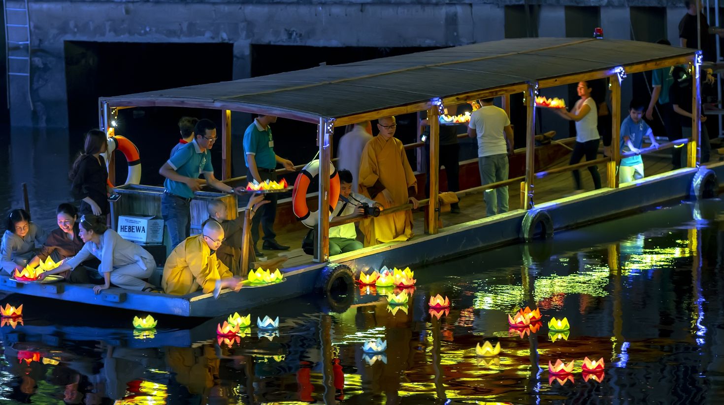 People placing lanterns in the river on a boat which you can see in Vietnam