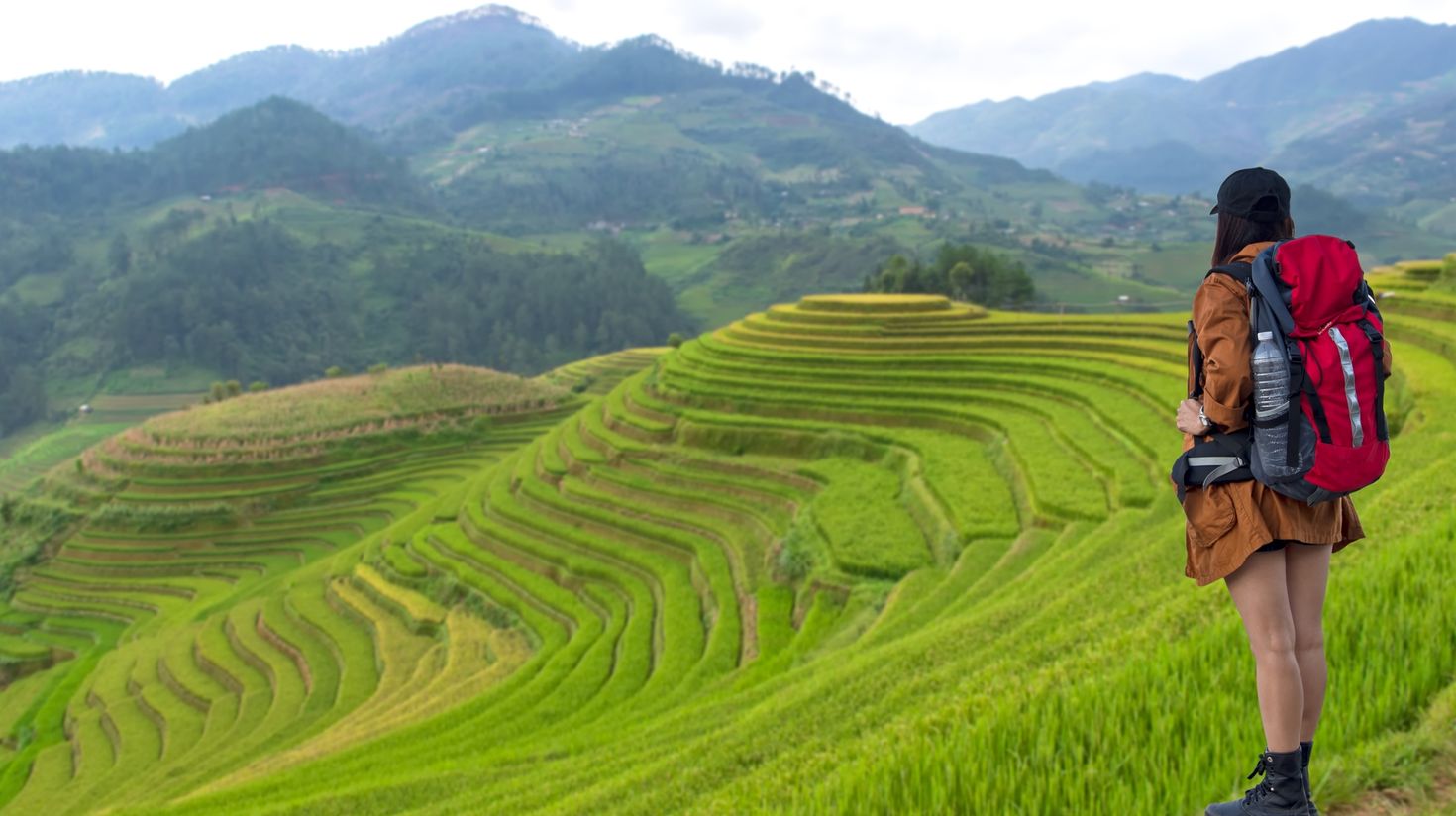 A hiker in the mountains with backpack near rice terraces in Vietnam.