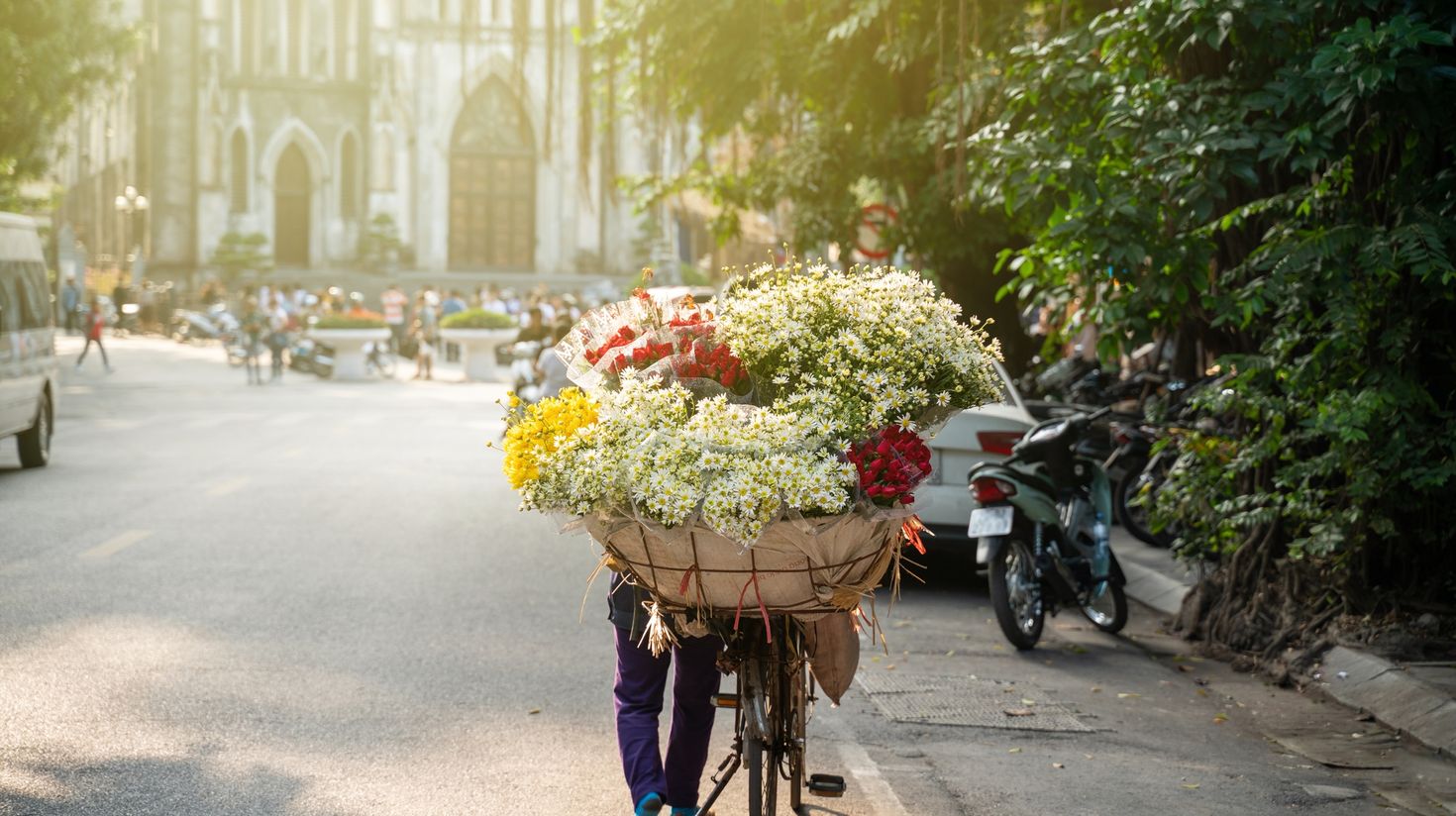 A flower vendor in Hanoi with St. Joseph Cathedral church in background.