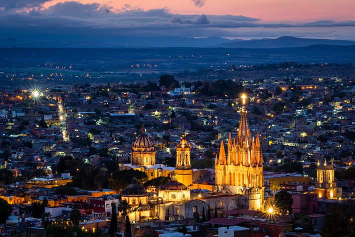 A well lit cathedral and the town at dusk in Mexico