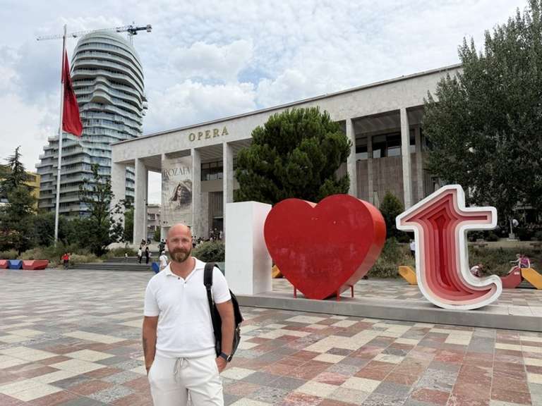 A young man stands in front of an iconic landmark somewhere in the Balkans