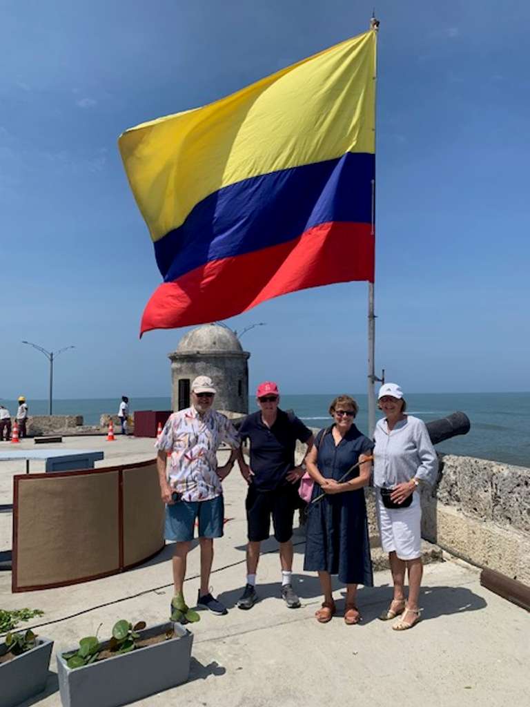 Two couples with Colombia flag waving in the background in a city wall