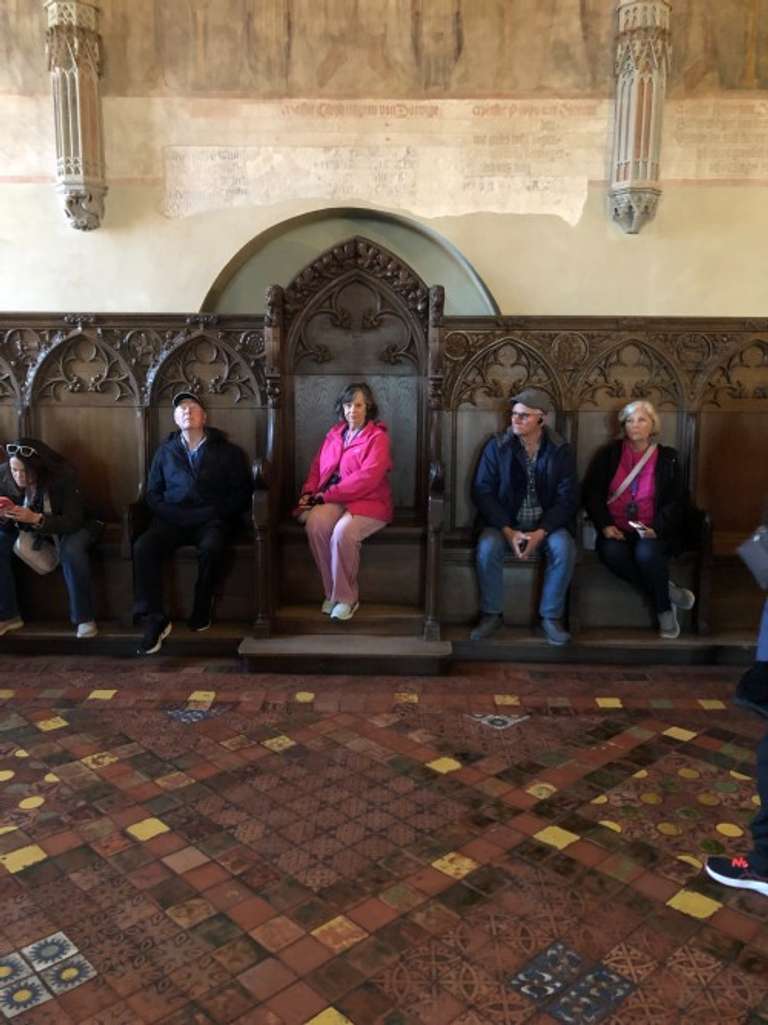 A group of elderly travelers pose as they sit on wooden chairs
