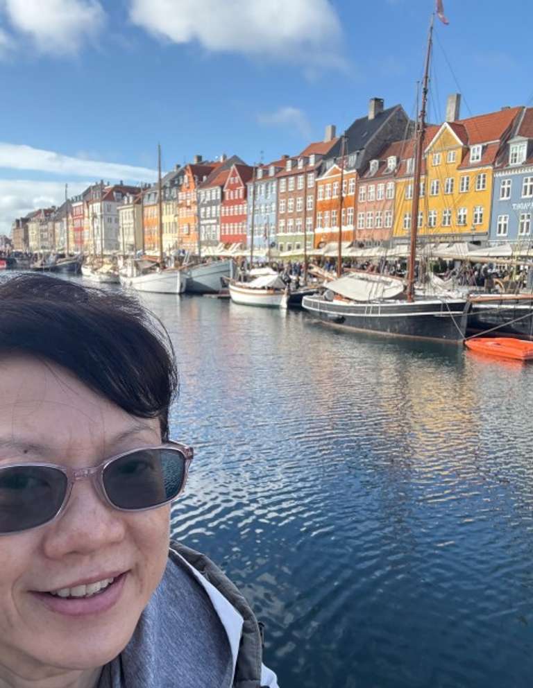 Selfie of a woman in glasses with the canal and the colorful houses of Copenhagen in the background